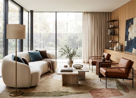 Tendencias en decoración de salón Salón moderno con sofá curvo, iluminación de diseño, muebles de madera y decoración en tonos neutros siguiendo las últimas tendencias de interiorismo.