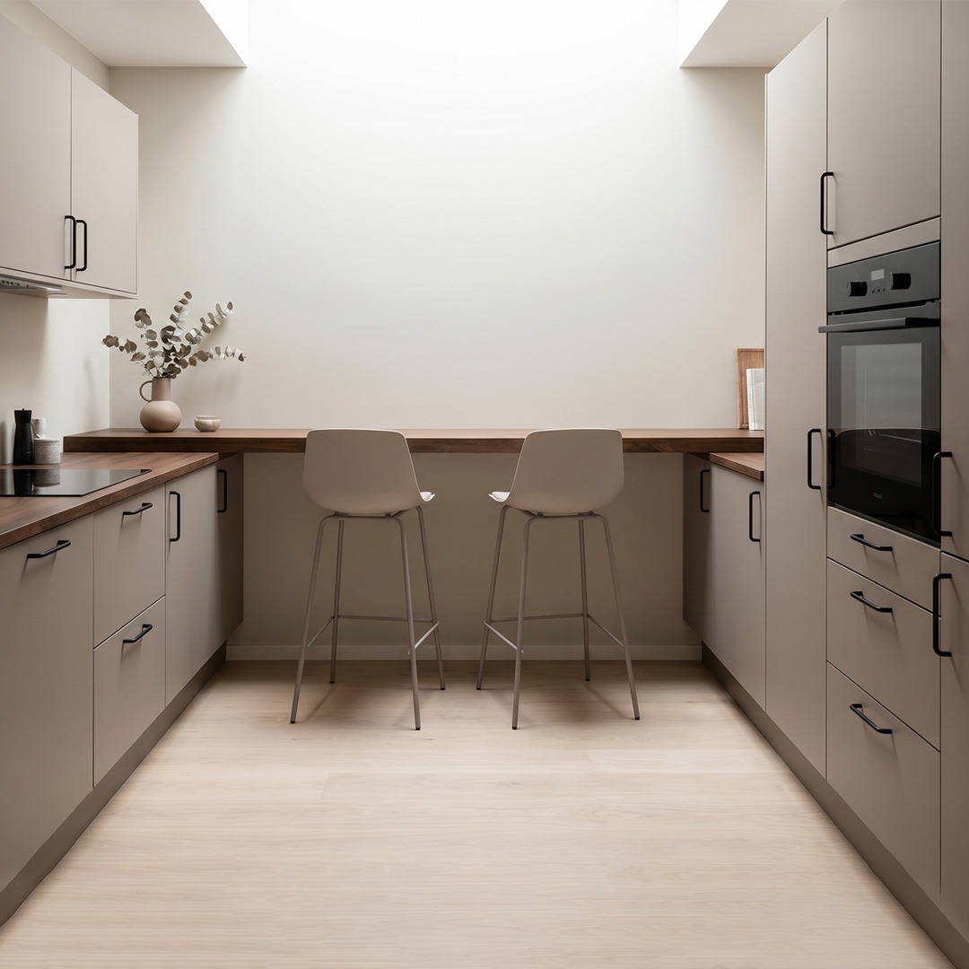 Cocina moderna con barra de desayuno integrada y taburetes altos gris topo Cocina moderna compacta con barra desayunadora de madera, muebles beige y dos taburetes altos para comedor diario.