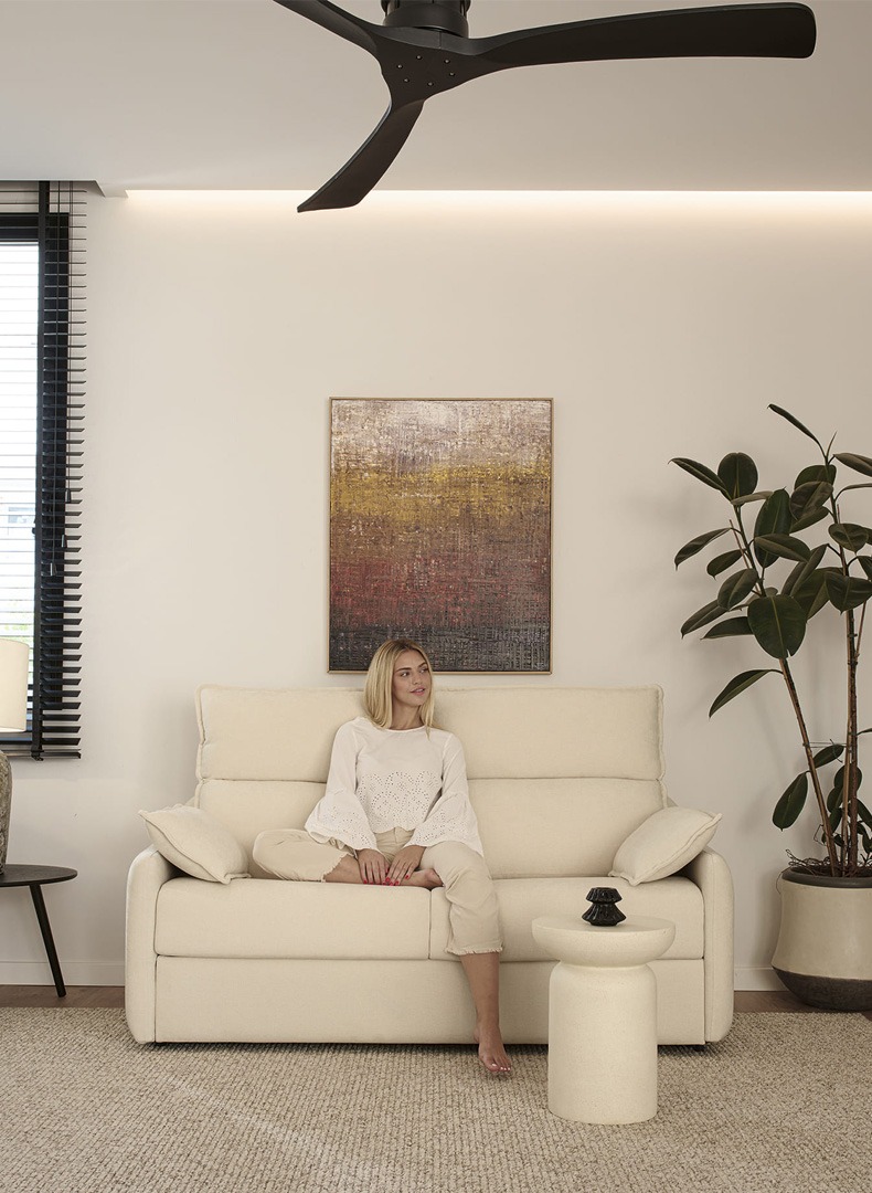 Cómo elegir el sofá cama más adecuado Sofá cama de tres plazas en un salón moderno con una mujer sentada