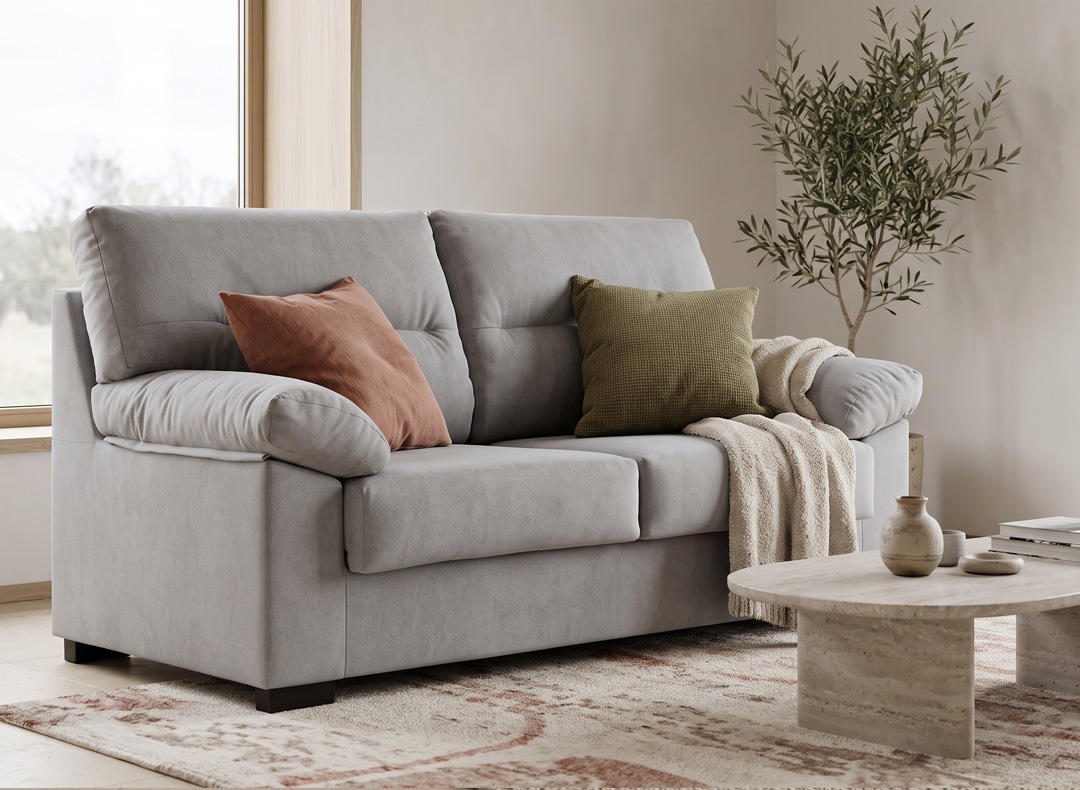 Cómo combinar un sofá gris con cojines de colores Sofá gris claro decorado con cojines terracota y verde oliva y una manta de textura en un salón luminoso.