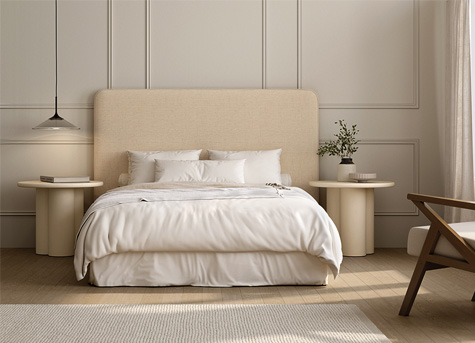 Dormitorio moderno con cama tapizada beige y decoración minimalista Dormitorio principal de estilo moderno con cama tapizada en color beige, ropa de cama blanca y mesillas redondas de madera clara en un ambiente luminoso y minimalista.